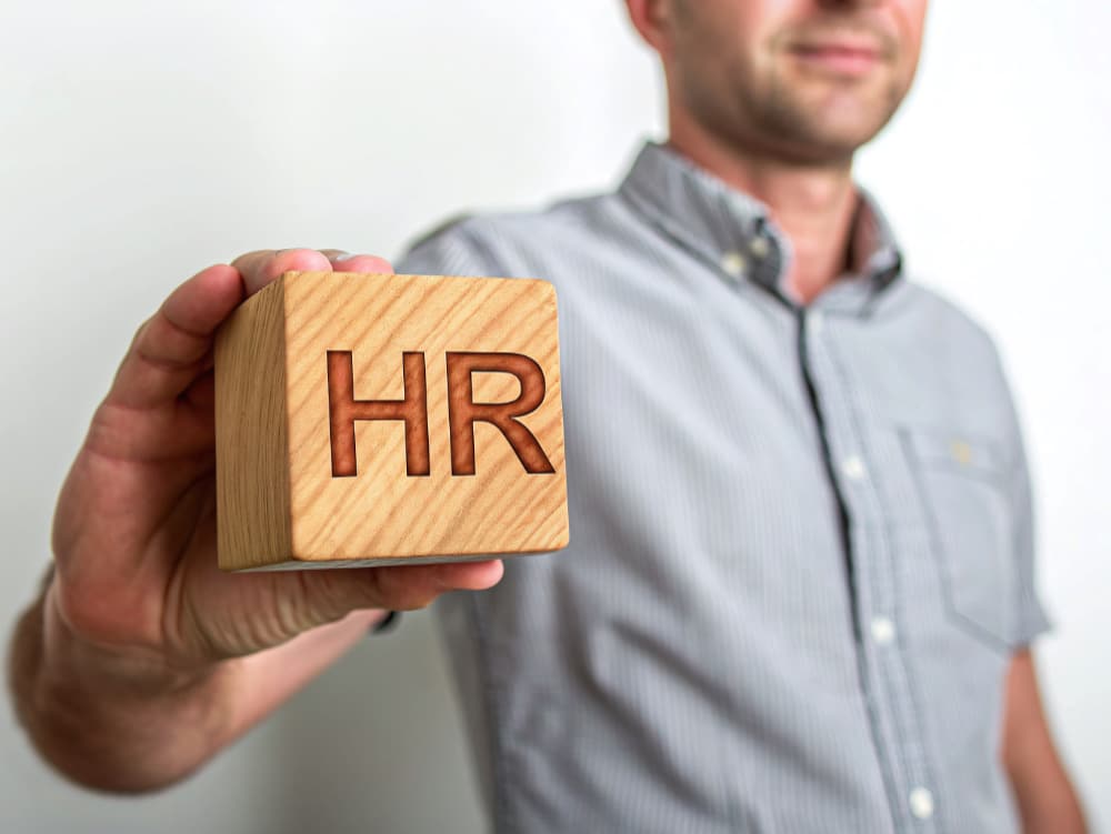 Human resources professional holding wooden block with HR lettering